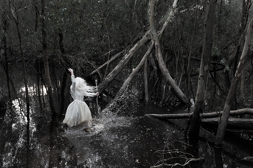 A woman in a white dress, possibly a white witch, standing in a river